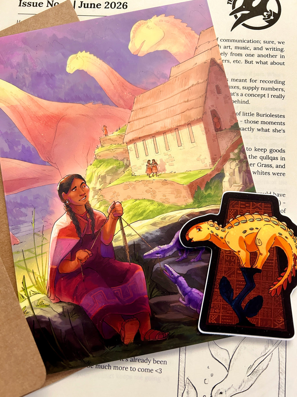 An illustrated art print featuring a woman reading a khipu in a landscape with sauropods in the background, and a small dinosaur-shaped sticker in the foreground.